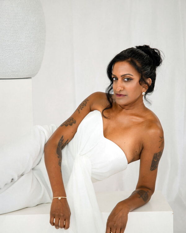 Braut im weissen Outfit liegend auf heller Sitzfläche – Brautstyling